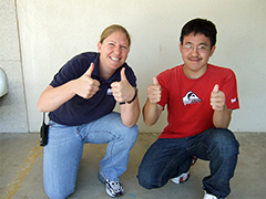 counselor and boy kneeling giving a thumbs up sign