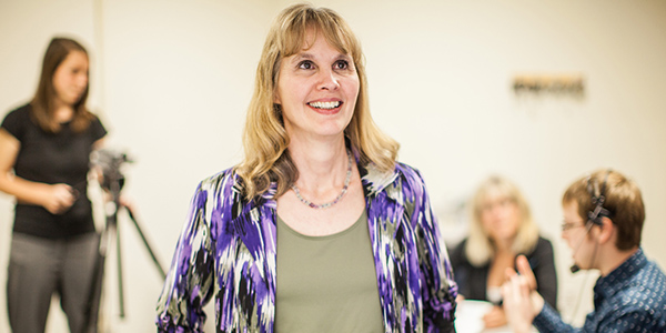 Dr. Karen Emmorey standing in front of female with video camera and male with headset in distance.